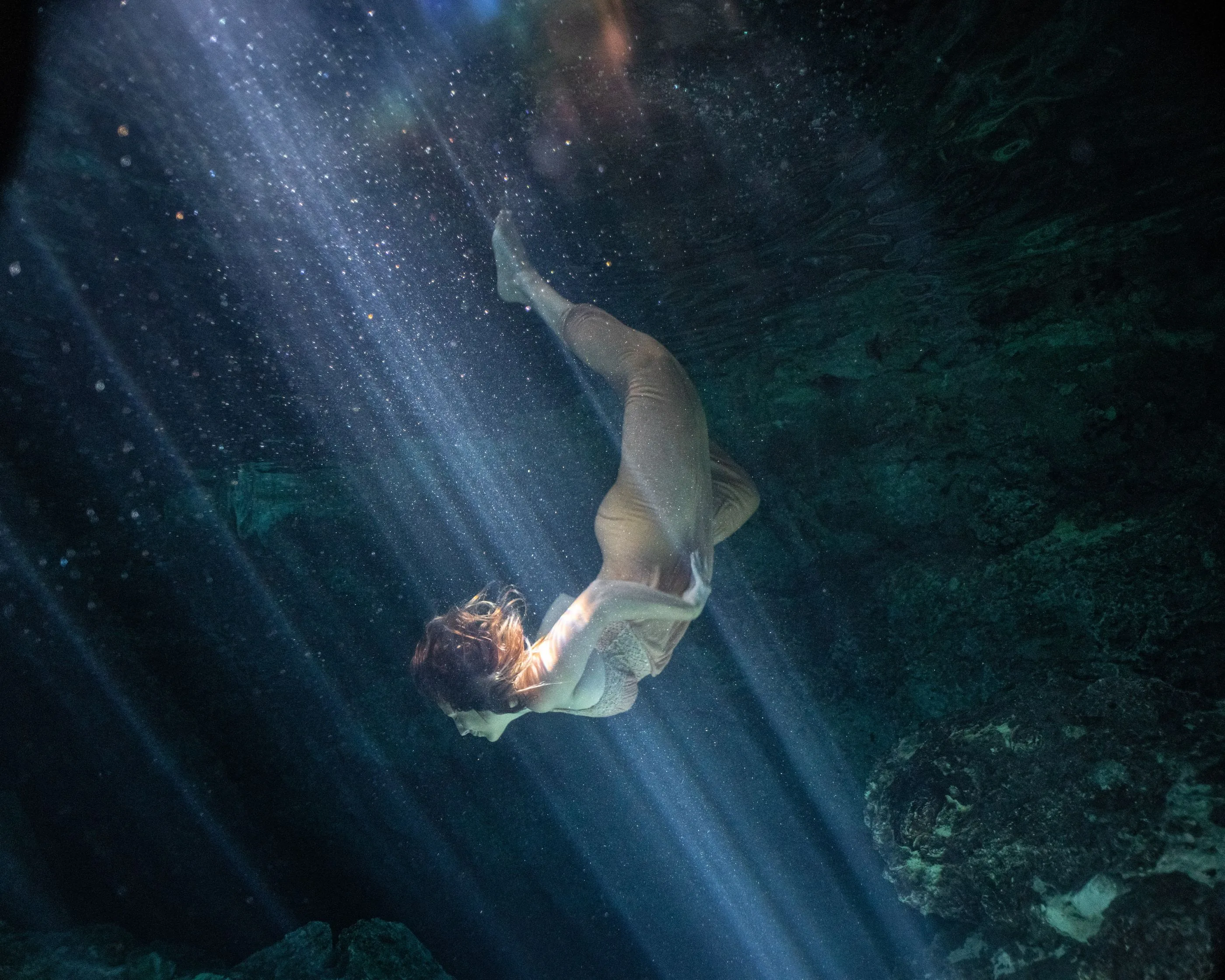A woman suspended in the light of a cenote