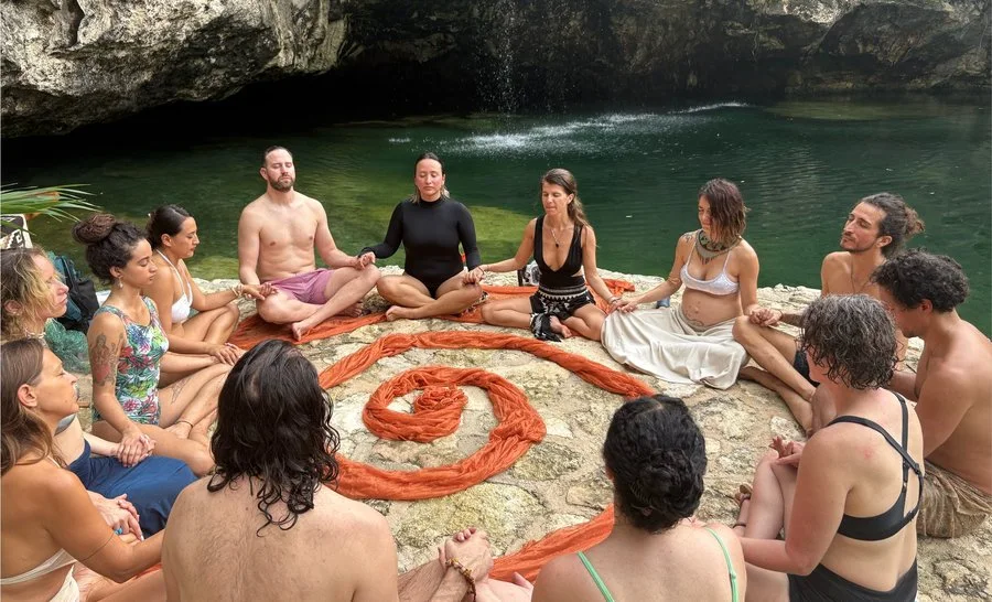 A circle of people meditating beside a cenote in the Riviera Maya
