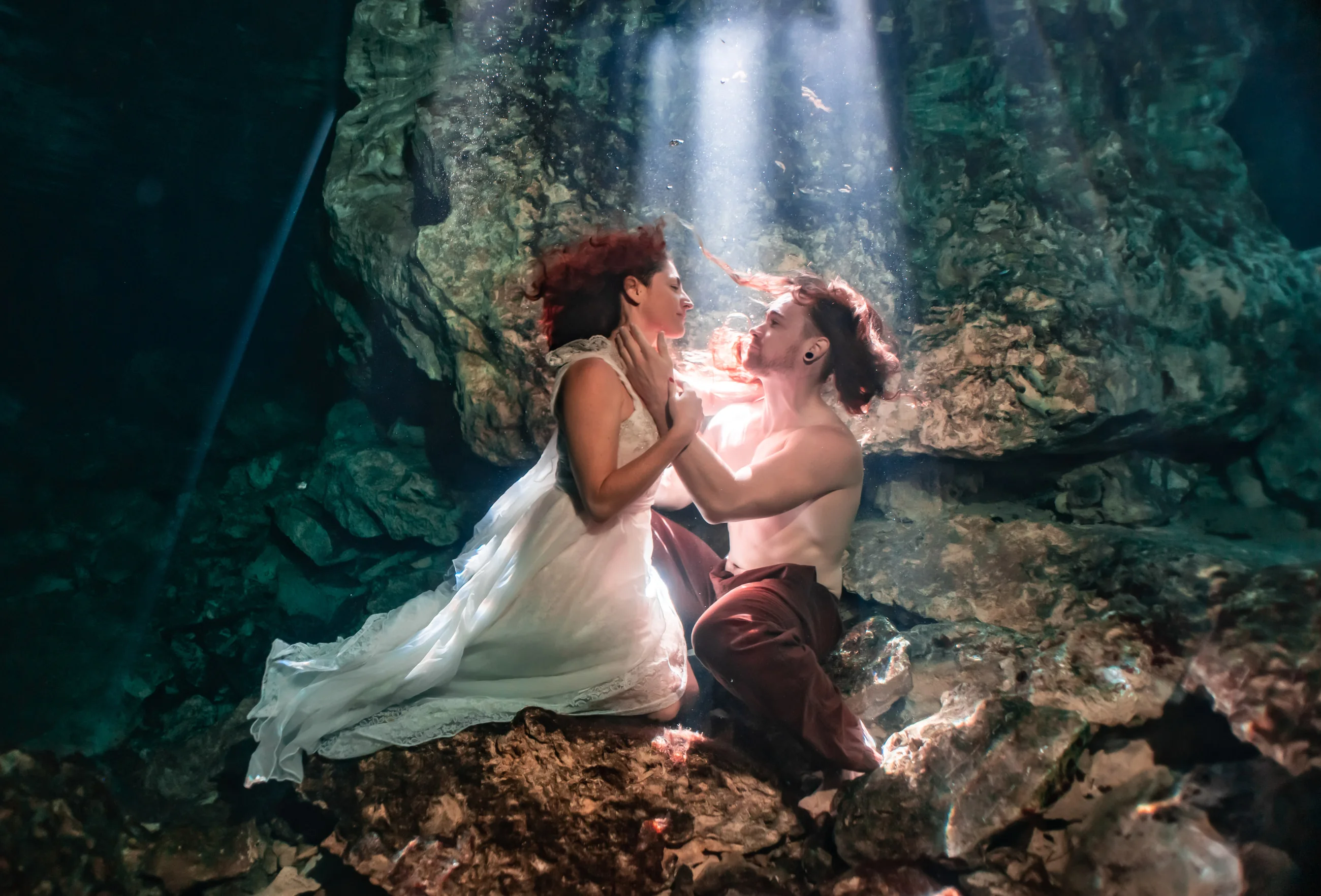 A couple meeting in a shaft of light in a cenote